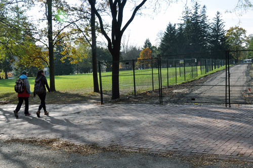 Students walk by the fence that stretches across Johnston Green.